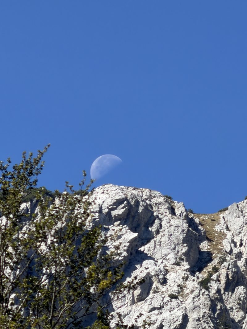 Moon in a Blue Sky Above a Rocky Peak