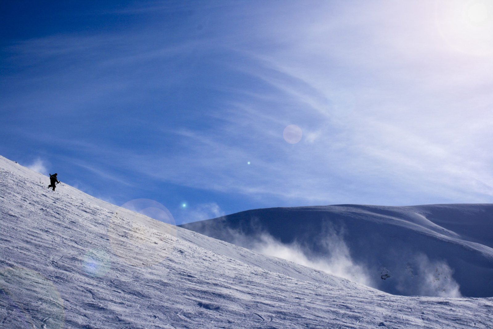 Hiker on a Snowy Slope Under a Blue Sky